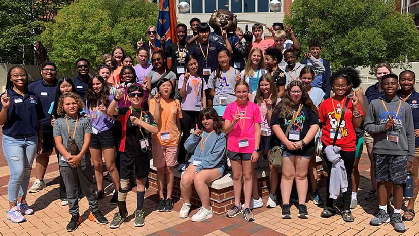 A large group of campers and counselors stand for a picture with the Aubie statue