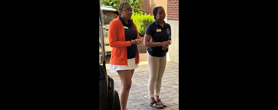 2 female student leaders introduce themselves to a group outside a building