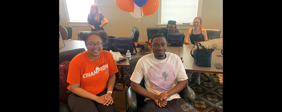 3 female students and 1 male student sit for a celebration in a conference room and smile for a picture