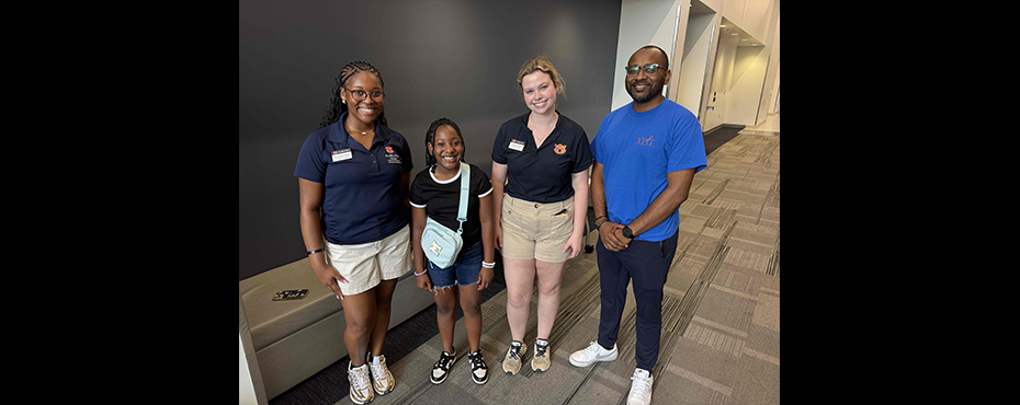 2 female student ambassadors stand for a picture with a father and daughter at an event