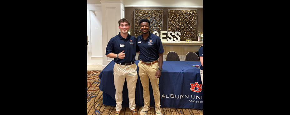 2 male student workers smile for a picture at a conference in a foyer ballroom area
