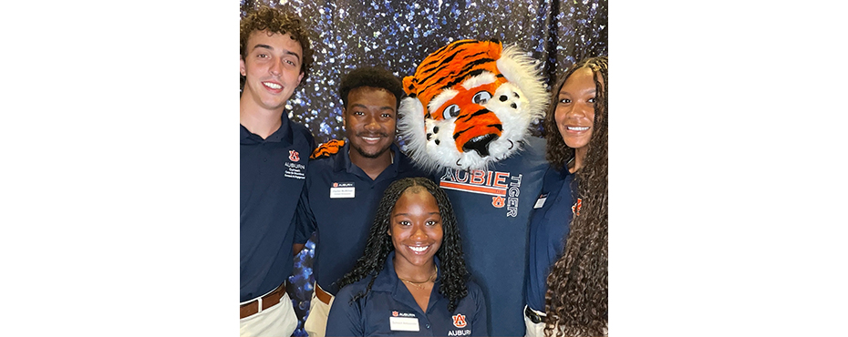 2 female and 2 male Outreach Ambassadors pose for a picture with Aubie at an event