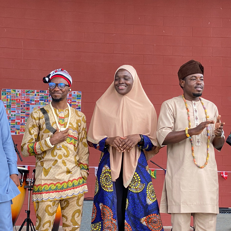 Two males and a female on stage wearing cultural attire