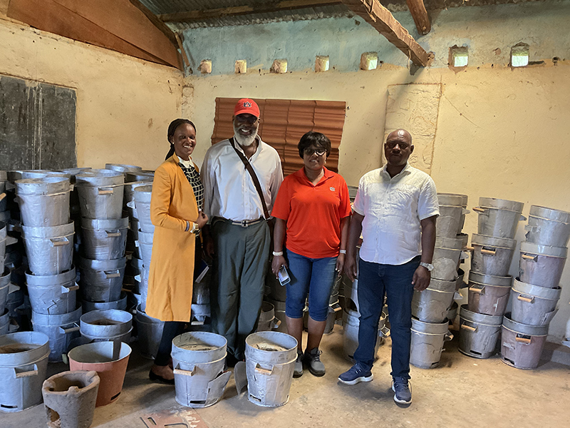 group of four standing in front of metal water buckets