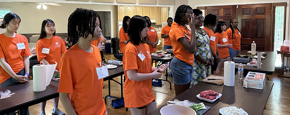 Students standing behind tables with cooking ingredients