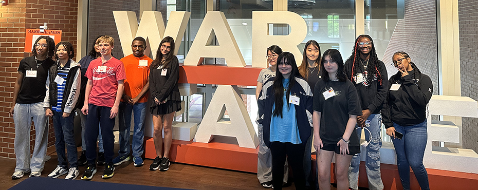 12 students standing in front of 'WAR EAGLE' letters