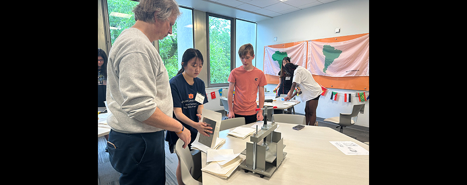 Two students and a man making sheets of paper