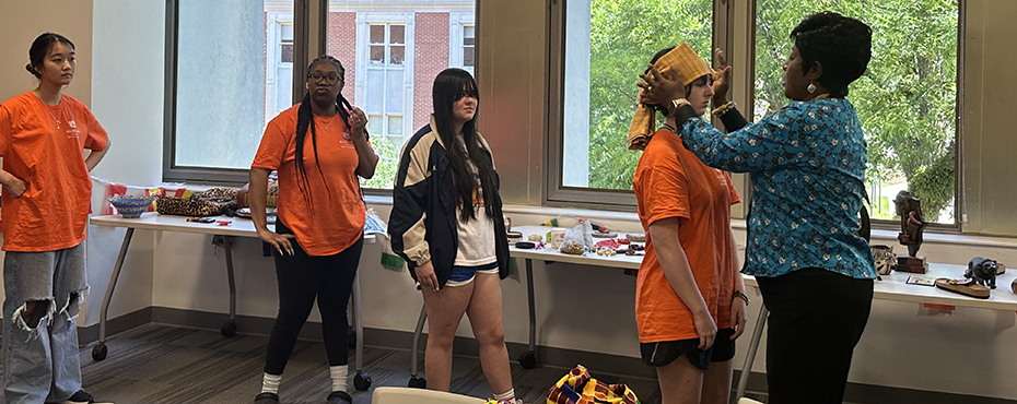 Women puts a hair band on a student while three other students watch.