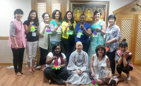 Group of people pose for a picture, many holding decorative ornaments