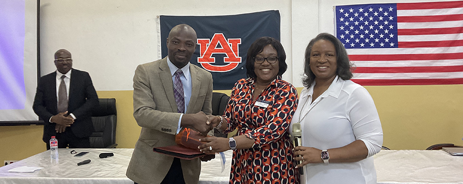 Two women from Auburn University shaking a man's hand