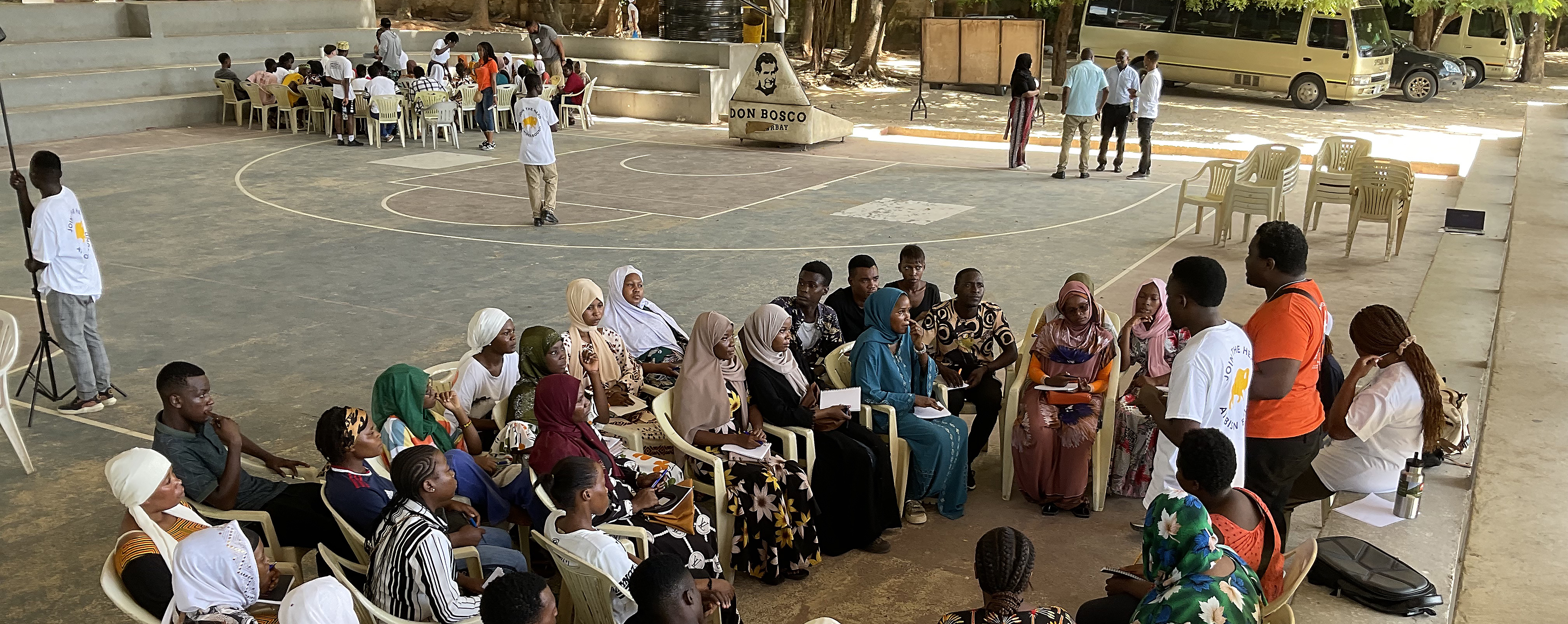 Large group of students sitting and being trained by university students.