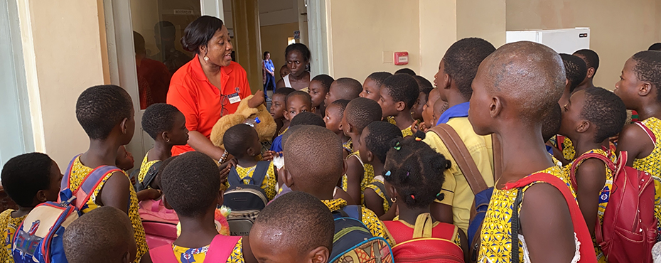 woman speaks in front of a group of children