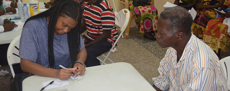 two people sitting at a table, one writing on a notepad