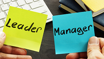 someone holding 2 post-it notes - one says leader one says manager