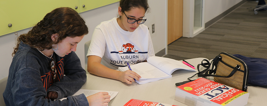 Two female campers read their ACT books.