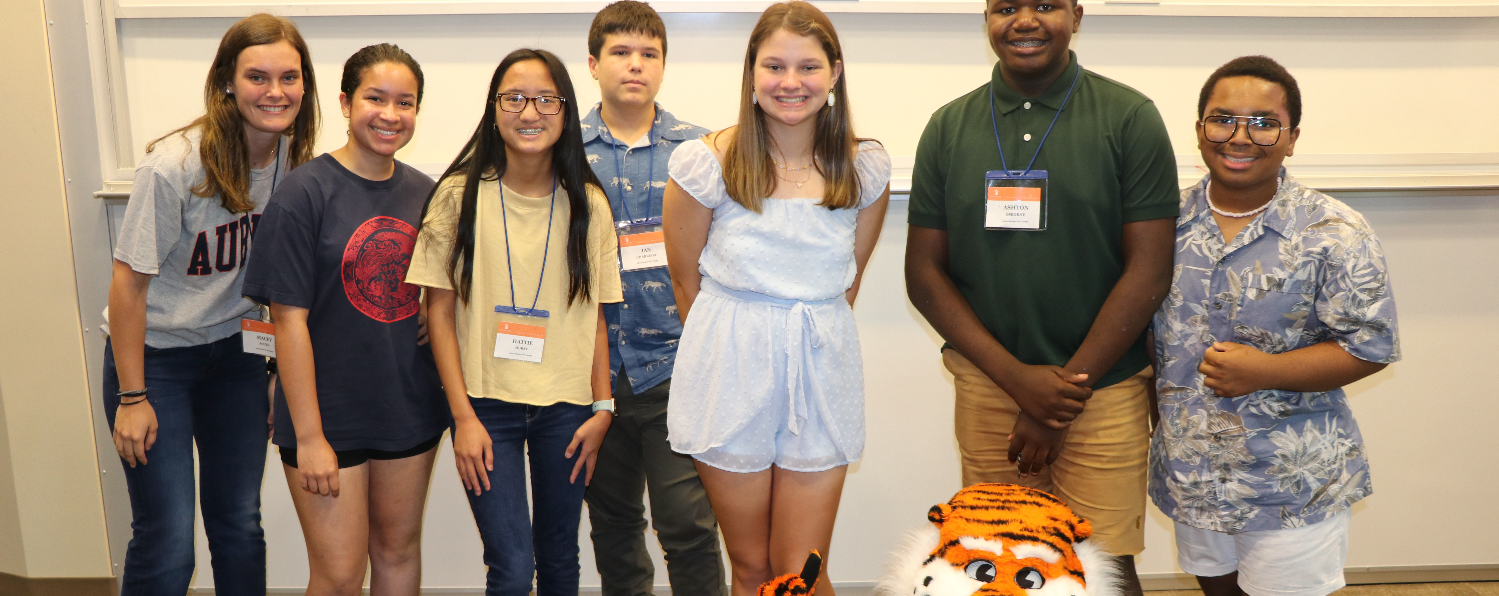 A group of campers pose for a picture while Aubie the Tiger lounges on the floor.