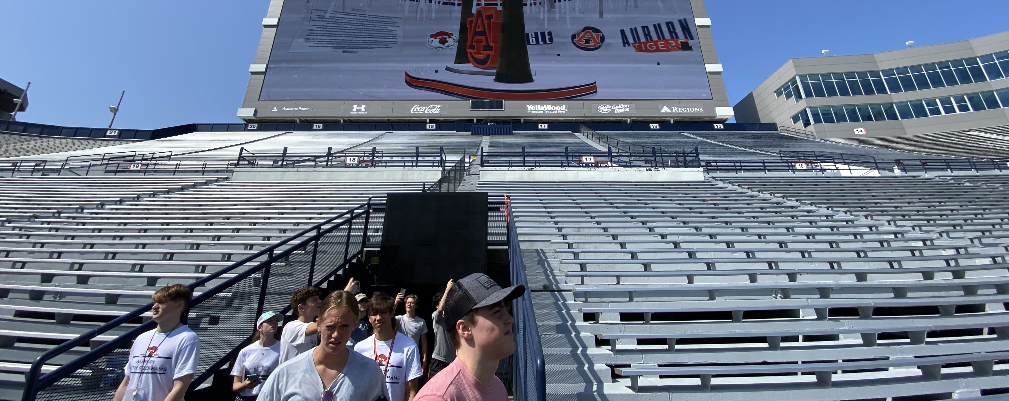 Students walk into Jordan-Hare Stadium with the jumbotron behind them.