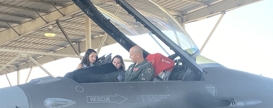 Students climb up to look inside an airplane at Tuskegee airfield.