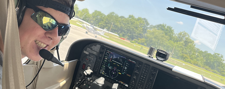 A male student pilots an aircraft at the Auburn Airport.