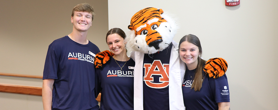 3 camp staff members posing with aubie the tiger mascot