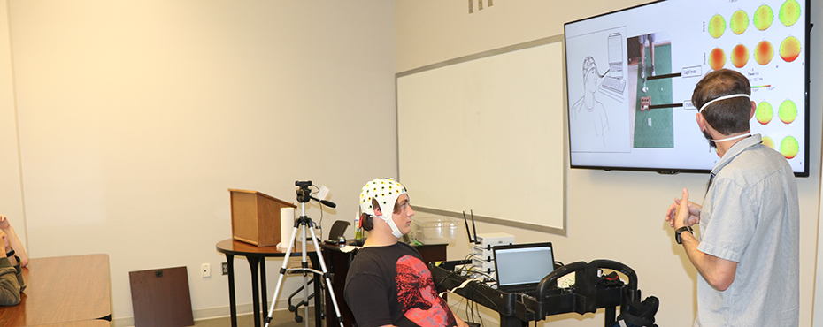 A male camper with an MRI cap on waches an instructional video.