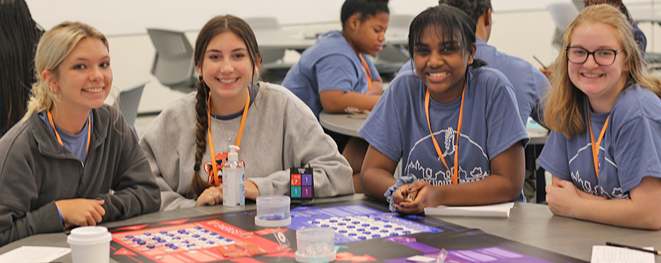 Students playing a pharmacy game around a table