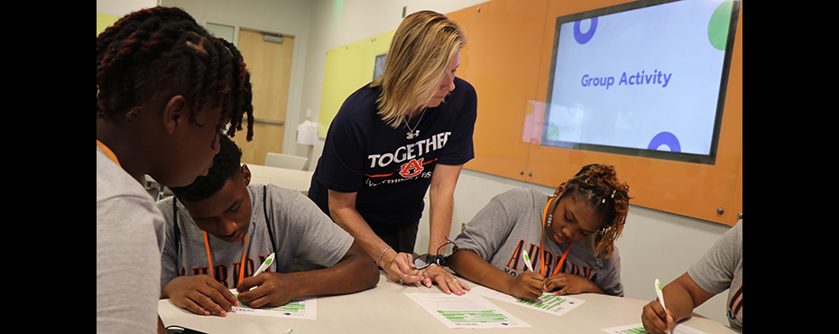 Teacher assists students with work in classroom.