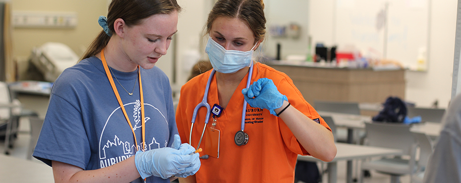 Student holds needle while instructor stands by and assists
