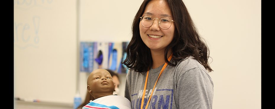Student holding infant doll