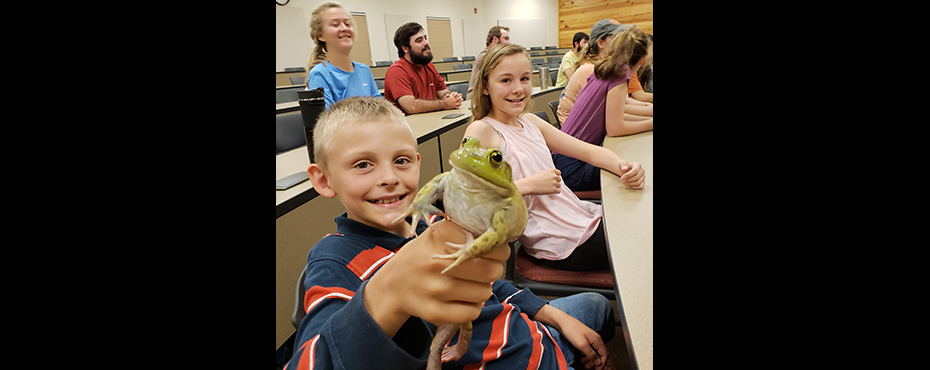 Boy holds a green frog.