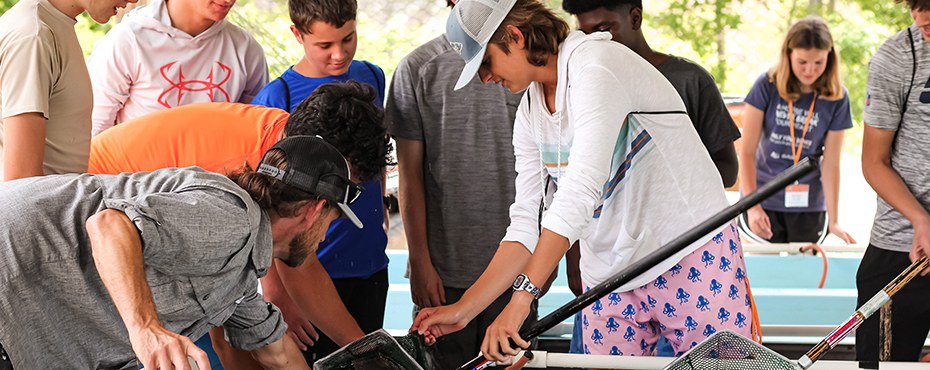 Group of campers stand around fishing net look at contents