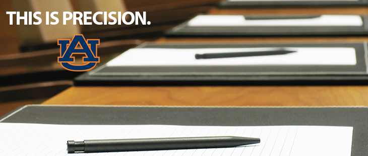 notepads and pens neatly laid out on a conference table. there is a text overlay that says "this is precision"