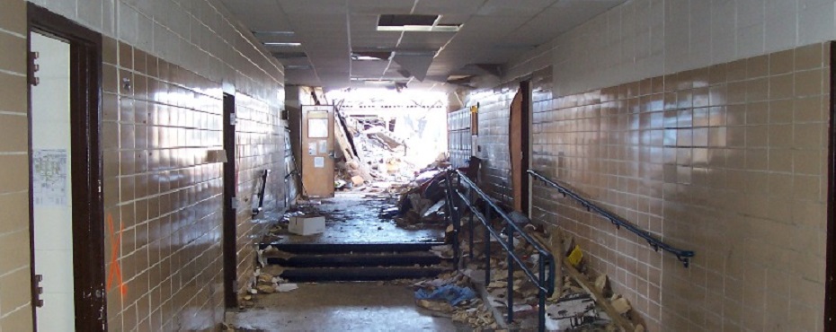 tInterior of school hallway looking toward open space where roof collapsed.
