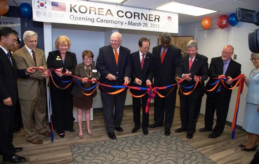 Group of people with scissors statnd behind red ribbon ready to cut as part of an opening ceremony