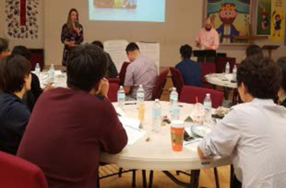 people sitting at round tables listening to a presentation