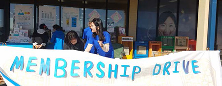 volunteer standing behind a membership drive sign