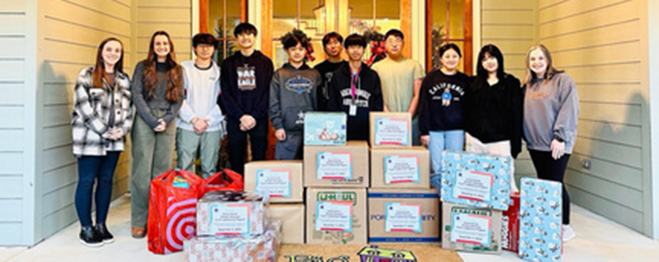 students standing behind a pile of Christmas gifts