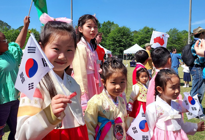 students in traditional garments waving Korean flags