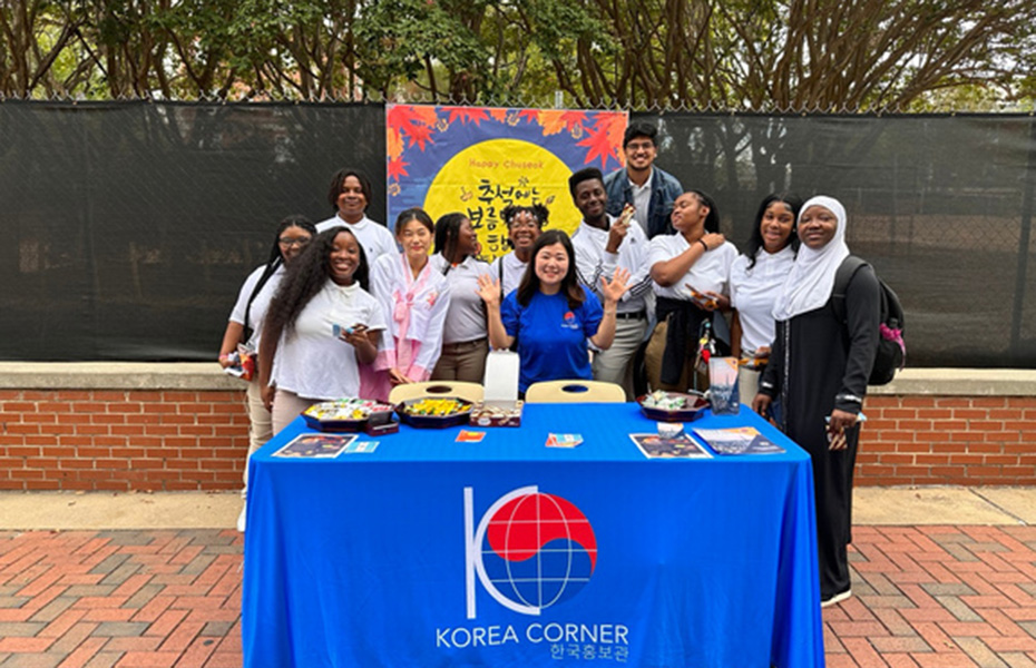 volunteers stand behind a Korea Corner table set up on a walkway
