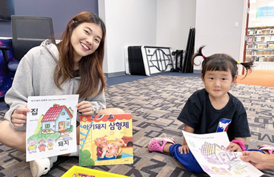 two students sitting on the floor displaying drawings