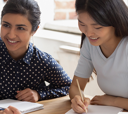 Students of different ethnicities sit around table doing schoolwork
