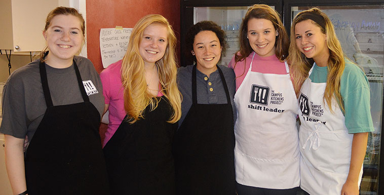 Group of students smiling at camera in the kitchen